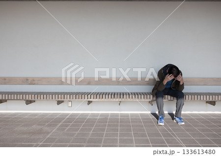 ベンチに座って頭をかかえてがっくりとうなだれている一人の中高年男性 ベンチに座って頭をかかえてがっくりとうなだれている一人の中高年男性 133613480