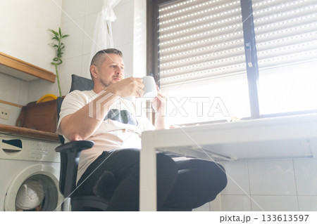 Man drinking coffee enjoying morning light at home 133613597