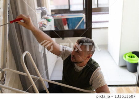 Man concentrating painting apartment wall home improvement project 133613607