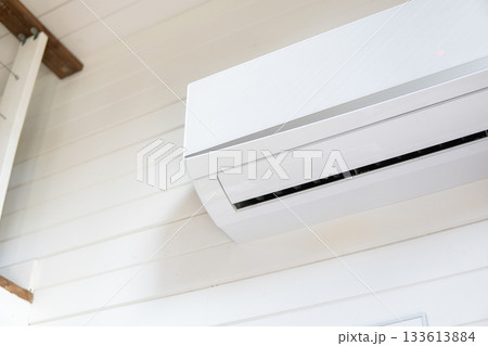 Air conditioner installed on white wall in bright interior of wooden house Air conditioner installed on white wall in bright interior of wooden house 133613884