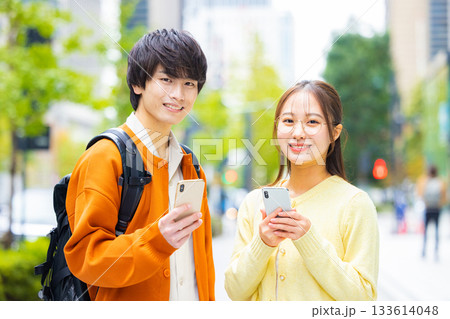 街中でスマホを見る若い男女 133614048