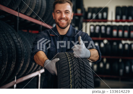 Man worker is maintenance station with tires, wheels 133614229