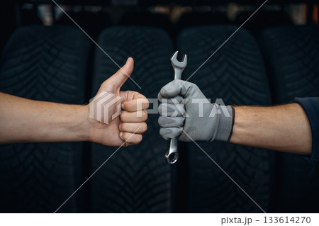 Automotive concept, repair, two male hands, one is holding wrench, ready to repair, another one with thumb up 133614270
