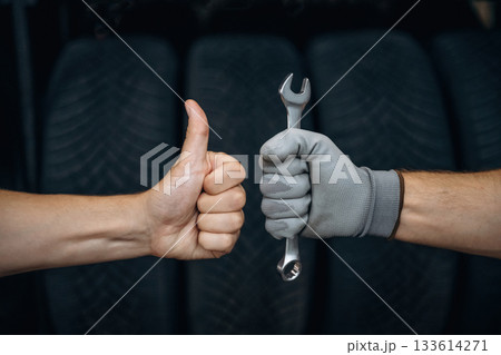 Automotive concept, repair, two male hands, one is holding wrench, ready to repair, another one with thumb up 133614271