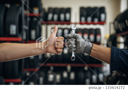 Automotive concept, repair, two male hands, one is holding wrench, ready to repair, another one with thumb up 133614272