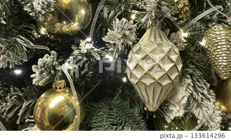 Luxury shiny Christmas tree with golden and transparent metallic balls, pine cones, leaves and lights garland. Xmas holiday card. Close up. Luxury shiny Christmas tree with golden and transparent metallic balls, pine cones, leaves and lights garland. Xmas holiday card. Close up. 133614296