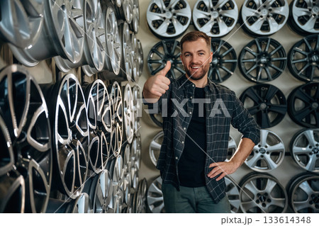 Thumb up, gesture. Man worker is maintenance station with tires, wheels 133614348