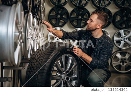 Sitting, professional man worker is maintenance station with tires, wheels Sitting, professional man worker is maintenance station with tires, wheels 133614362