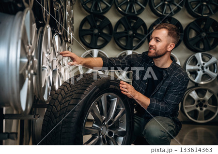 Sitting, professional man worker is maintenance station with tires, wheels Sitting, professional man worker is maintenance station with tires, wheels 133614363