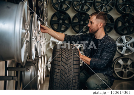 Sitting, professional man worker is maintenance station with tires, wheels Sitting, professional man worker is maintenance station with tires, wheels 133614365
