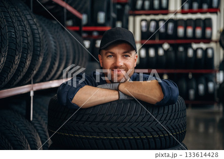 Inside of the wheels, having fun. Man worker is maintenance station with tires 133614428