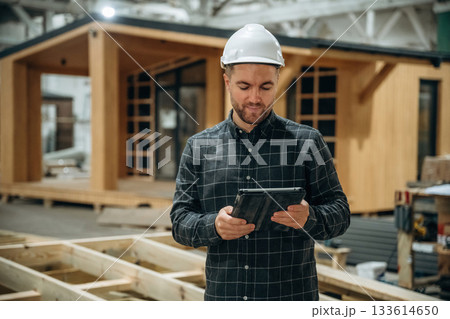 In white helmet. Male builder is at construction of wooden house In white helmet. Male builder is at construction of wooden house 133614650