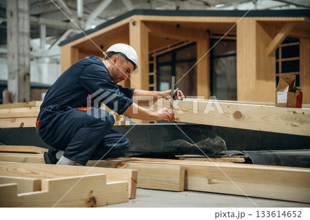 Measuring the planks. Male builder is at construction of wooden house Measuring the planks. Male builder is at construction of wooden house 133614652