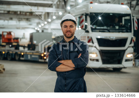 Standing in front of a truck. Male worker is in the modern warehouse or manufacturing company 133614666