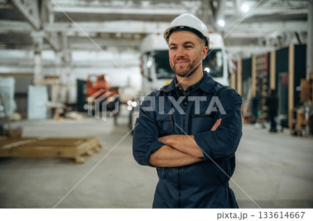 Standing in front of a truck. Male worker is in the modern warehouse or manufacturing company 133614667