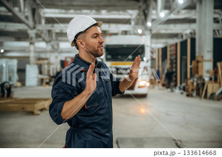 Hands gestures, helps to park the vehicle. Male worker is in the modern warehouse or manufacturing company 133614668
