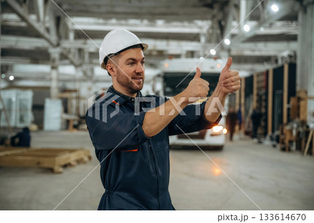 Hands gestures, helps to park the vehicle. Male worker is in the modern warehouse or manufacturing company Hands gestures, helps to park the vehicle. Male worker is in the modern warehouse or manufacturing company 133614670