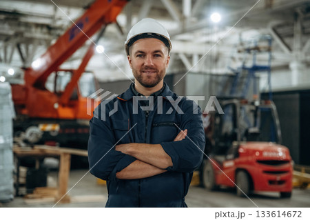 Front view, standing. Male worker is in the modern warehouse or manufacturing company 133614672
