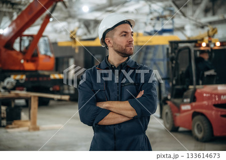 Front view, standing. Male worker is in the modern warehouse or manufacturing company 133614673