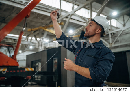 Controlling the process, hand gestures, communication. Male worker is in the modern warehouse or manufacturing company Controlling the process, hand gestures, communication. Male worker is in the modern warehouse or manufacturing company 133614677