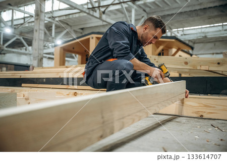 Male builder is at construction of wooden house Male builder is at construction of wooden house 133614707