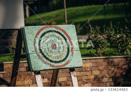 Close up view of dart holes on board due to throwing darts a bunch of times, outdoors, sunlight Close up view of dart holes on board due to throwing darts a bunch of times, outdoors, sunlight 133614983