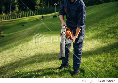 Working by using leaf blower. Professional gardener is on the lawn Working by using leaf blower. Professional gardener is on the lawn 133615097