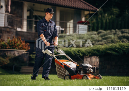 Fuel powered lawn mover, cutting the grass. Professional gardener is on the lawn Fuel powered lawn mover, cutting the grass. Professional gardener is on the lawn 133615129