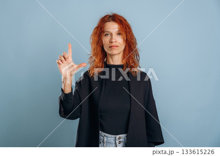 Showing the letter. Woman is in the studio against background Showing the letter. Woman is in the studio against background 133615226