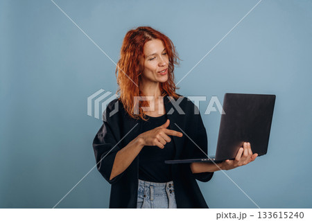 Holding laptop. Woman is in the studio against background Holding laptop. Woman is in the studio against background 133615240
