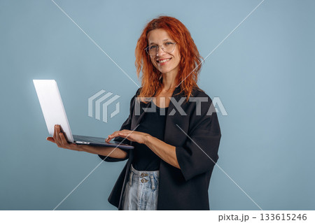 Laptop is in the hand. Woman is in the studio against background Laptop is in the hand. Woman is in the studio against background 133615246