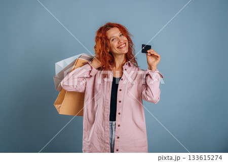 Credit card, holding shopping bags. Woman is in the studio against background Credit card, holding shopping bags. Woman is in the studio against background 133615274