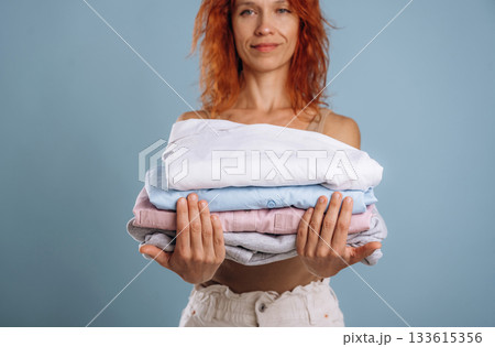 After the washing, holding fresh clothes. Woman is in the studio against background 133615356