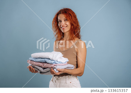 After the washing, holding fresh clothes. Woman is in the studio against background 133615357
