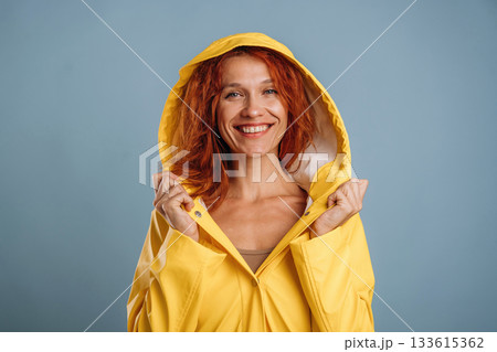 Smiling, in yellow raincoat. Woman is in the studio against background Smiling, in yellow raincoat. Woman is in the studio against background 133615362