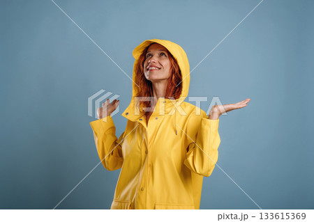 Looking for a rain, in yellow coat. Woman is in the studio against background Looking for a rain, in yellow coat. Woman is in the studio against background 133615369