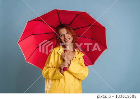 Red umbrella and yellow raincoat. Woman is in the studio against background Red umbrella and yellow raincoat. Woman is in the studio against background 133615388