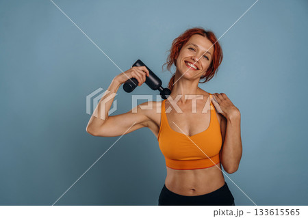 Professional electric automatic massager. Woman is in the studio against background 133615565