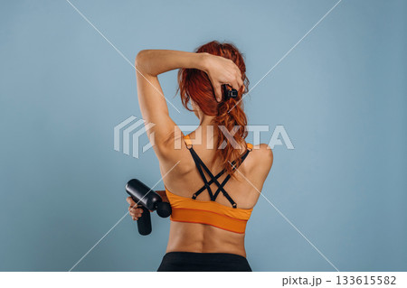 Professional electric automatic massager. Woman is in the studio against background Professional electric automatic massager. Woman is in the studio against background 133615582