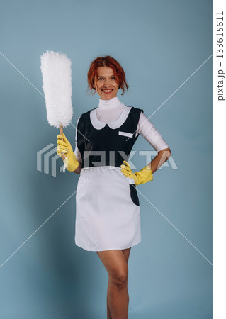 Maid is with dust brush. Woman is in the studio against background 133615611