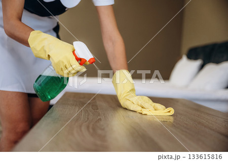 In yellow gloves, cleaning the place. Maid is working in modern hotel room In yellow gloves, cleaning the place. Maid is working in modern hotel room 133615816