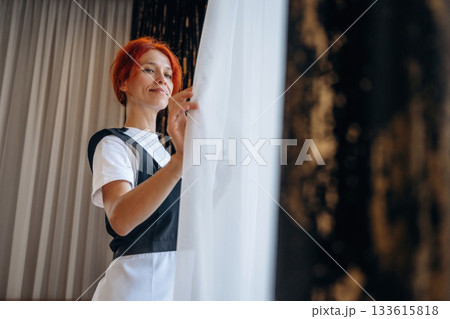 Maid is working in modern hotel room 133615818