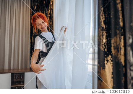 Maid is working in modern hotel room 133615819