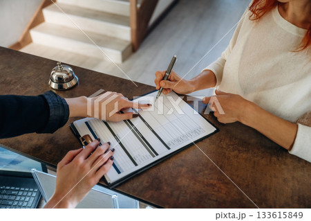 Registration process, document. Woman is at reception of the modern hotel Registration process, document. Woman is at reception of the modern hotel 133615849