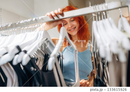 Redhead woman chooses clothes in retail store Redhead woman chooses clothes in retail store 133615926
