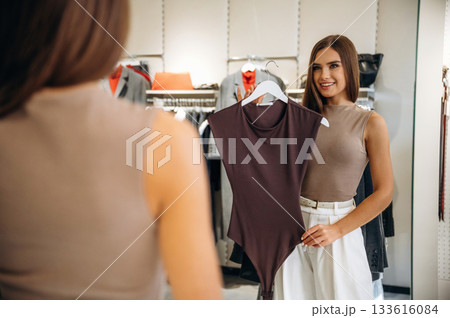 Looking at the mirror. Woman chooses clothes in retail store 133616084