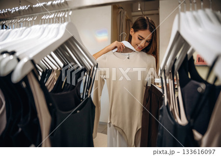 Feeling joy, cheerful. Woman chooses clothes in retail store Feeling joy, cheerful. Woman chooses clothes in retail store 133616097