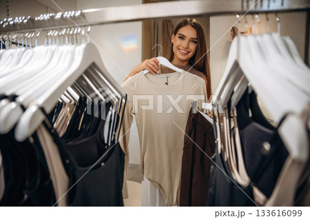 Feeling joy, cheerful. Woman chooses clothes in retail store 133616099