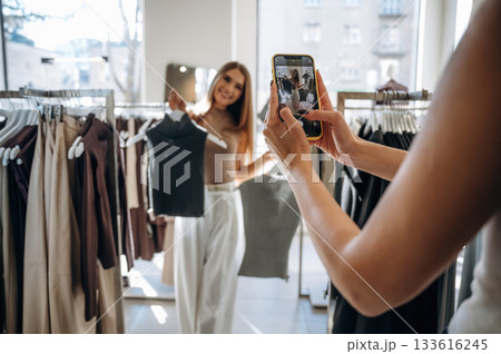 Two female friends are in the retail store, choosing clothes, shopping Two female friends are in the retail store, choosing clothes, shopping 133616245