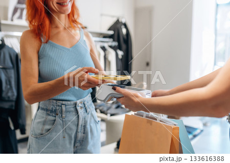 Detailed close up view. Woman is paying for clothes, in the retail store Detailed close up view. Woman is paying for clothes, in the retail store 133616388